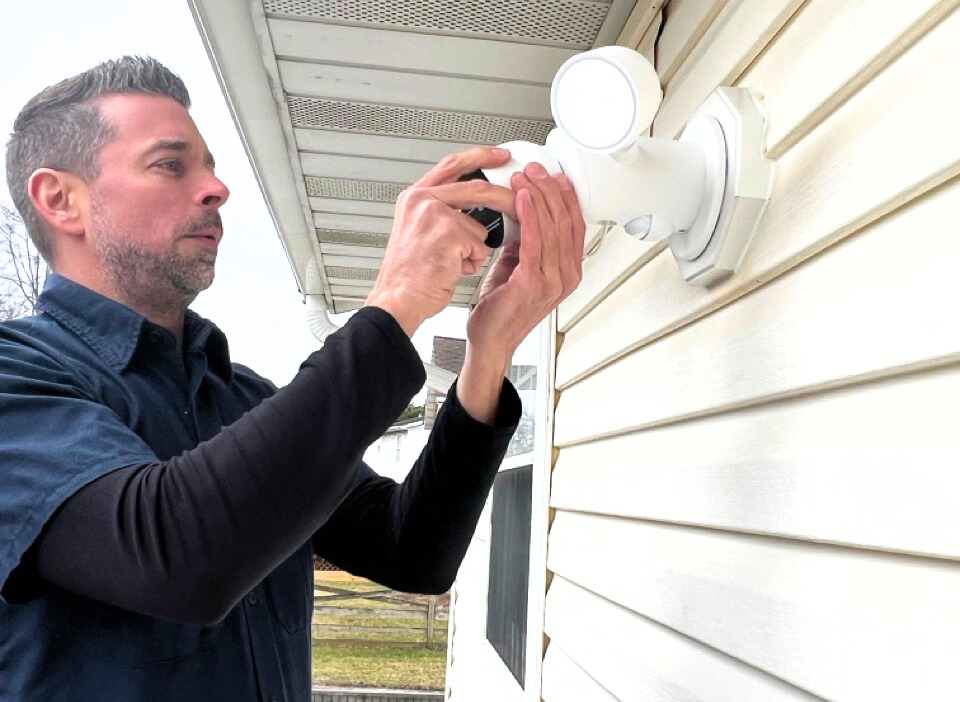 electrician installing an outdoor flood light with camera