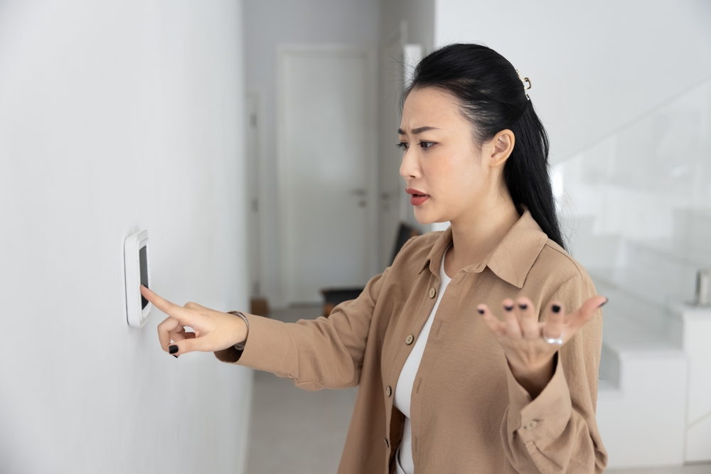 woman adjusts thermostat because her AC is running constantly and she isn't sure why